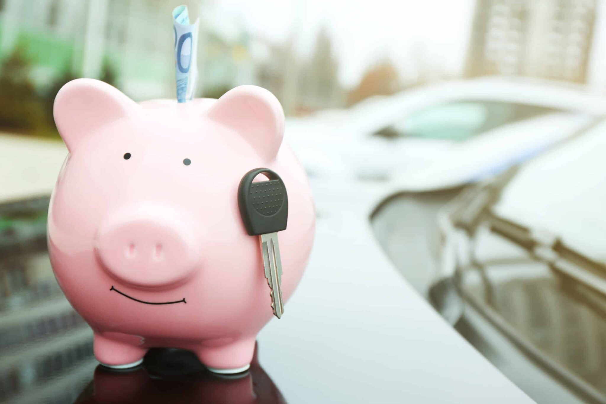 Spardose mit Bargeld und Autoschlüssel liegt auf der Motorhaube eines Fahrzeugs